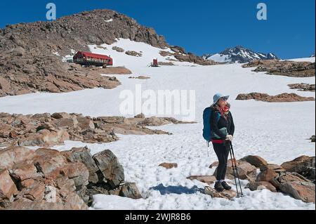 Sfidando i venti invernali, una donna escursionista si erge in cima a un terreno glaciale, circondato dalla bellezza mozzafiato della natura Foto Stock