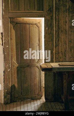 Vecchia porta di legno aperta attraverso la quale la luce entra e arriva nell'area inferiore dell'officina Foto Stock