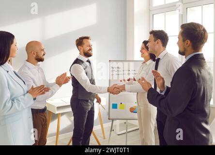 Il team Office celebra il successo e plaude ai colleghi per la presentazione aziendale Foto Stock
