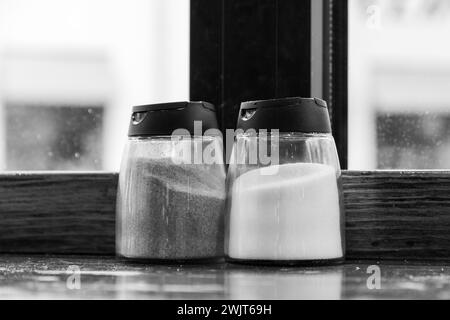 Salate e peperoni su un tavolo contro una finestra in una tavola calda. Immagine monocromatica Foto Stock