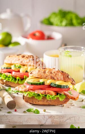 Panino fatto in casa servito con limonata in cucina. Sandwich con verdure e pollo al curry. Foto Stock