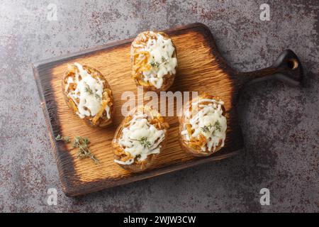 Zuppa di cipolle francese patate ripiene con un primo piano di formaggio sul bordo di legno sul tavolo. Vista dall'alto orizzontale Foto Stock