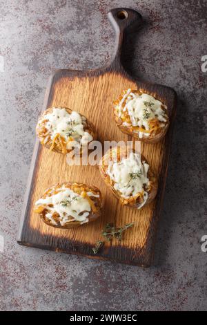 Patate al forno ripiene di cipolle caramellate e formaggio Gruyere da vicino in una ciotola sul tavolo. Vista dall'alto verticale Foto Stock