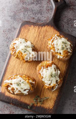 Patate al forno ripiene due volte con cipolle francesi e formaggio Gruyere da vicino in una ciotola sul tavolo. Vista dall'alto verticale Foto Stock