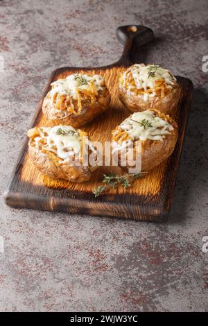 Patate al forno ripiene due volte con cipolle francesi e formaggio Gruyere da vicino in una ciotola sul tavolo. Verticale Foto Stock