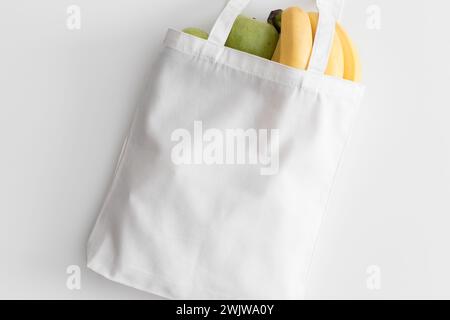 Borsa tote bianca con frutta su un tavolo bianco. Foto Stock