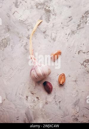 Spicchi d'aglio e bulbo in lampadine d'aglio su cemento leggero.Vista dall'alto spicchi d'aglio freschi. Concetto di stile di vita sano. L'aglio antivirale e medicinale aiuta Foto Stock