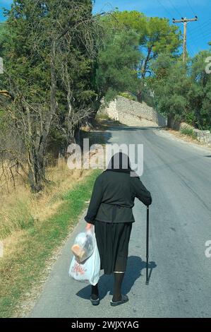 Donna anziana in tradizionale abbigliamento nero che cammina, Lefkas, isole Ionie, Grecia Foto Stock