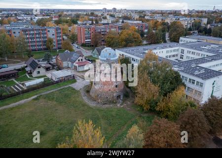 Fotografia con drone di un vecchio mulino a vento abbandonato in una città durante la soleggiata serata autunnale Foto Stock