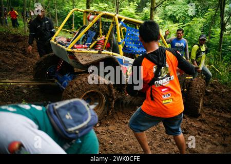 Il comitato organizzatore sta evacuando un'auto fuoristrada che si è schiantata su una pista fangosa durante la competizione IOF a Kediri, Giava Est, Indonesia Foto Stock