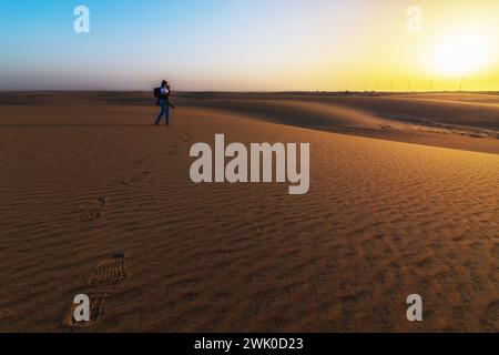 Il fotografo si trova da solo nel deserto lasciando passi di cibo a Dammam in Arabia Saudita. Splendido sfondo all'alba con una struttura di dune di sabbia Foto Stock