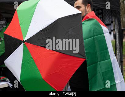 Il 17 febbraio 2024 si sono svolte manifestazioni in tutto il mondo per chiedere un cessate il fuoco a Gaza. Uomo che compra un ombrello dai colori palestinesi Foto Stock