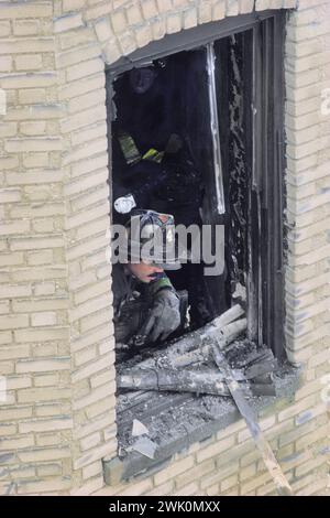 Vigile del fuoco o vigile del fuoco che rilevano danni da una finestra dell'edificio con vetro rotto. Scena del fuoco nel South Bronx, New York City USA Foto Stock