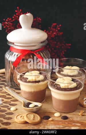 Panna cotta da dessert italiana con guarnizione al cioccolato. Panna cotta decorata con scoiattolo di cioccolato bianco su sfondo in legno. Foto Stock