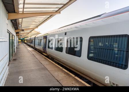 Treno passeggeri fermo in una piattaforma deserta della stazione al tramonto in estate Foto Stock