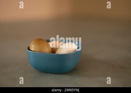 Le tre uova biologiche fresche in una ciotola su un tavolo verde di cemento Foto Stock