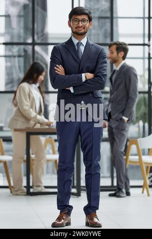 Bel giovane uomo d'affari con gli occhiali in piedi con fiducia in ufficio Foto Stock