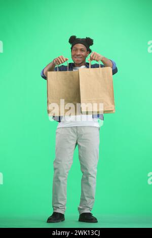 Un uomo, a tutta lunghezza, su sfondo verde, con le borse Foto Stock