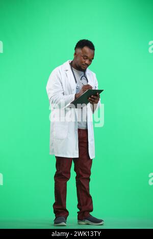 Il medico, a tutta altezza, su sfondo verde, scrive Foto Stock