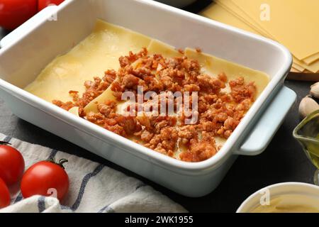 Cottura delle lasagne. Fogli di pasta, carne macinata nel vassoio da forno e pomodoro sul tavolo, primo piano Foto Stock