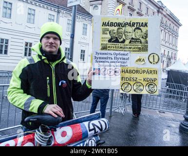 Budapest, Budapest, Ungheria. 17 febbraio 2024. Un attivista ungherese con la sua bici, reca un cartello con scritto "Partito della Guerra" di fronte a Varkert, dove il primo ministro ungherese VIKTOR ORBAN ha tenuto il suo discorso annuale e commentato tre dimissioni del presidente ungherese, KATALIN NOVAK; l'ex ministro e leader della Chiesa riformata ungherese, ZOLTAN BALOG e l'ex ministro della giustizia, JUDIT VARGA, a seguito dell'esposizione di un uomo perdonato l'anno scorso per aver coperto la pedofilia in una casa per bambini. La rivelazione ha causato imbarazzo e offuscato l'immagine della zona sicura ungherese e l'immagine di alto valore familiare. Foto Stock