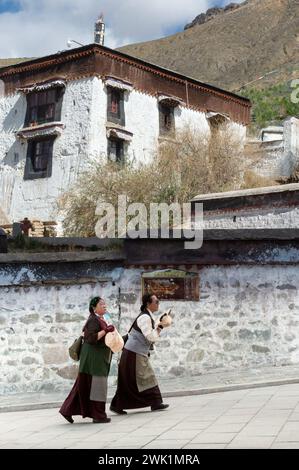 Due donne camminano lungo la parete esterna del monastero di Tashi Lhunpo a Shigatse, regione autonoma del Tibet, Cina. Foto Stock