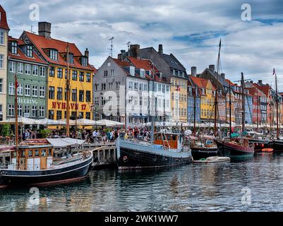 Barche e negozi fiancheggiano la storica e panoramica destinazione turistica del canale Nyhavn nel centro della città di Copenaghen, Danimarca. Foto Stock