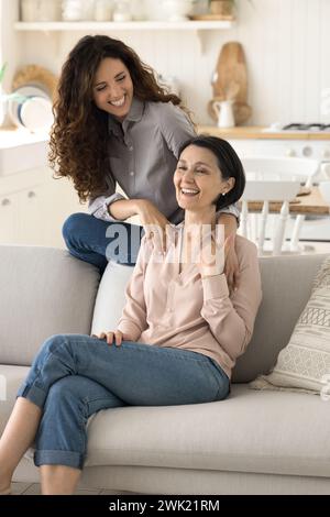 Donne multigenerazionali che ridono, scherzano, si siedono insieme sul divano Foto Stock
