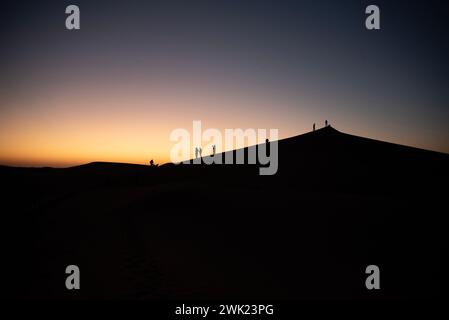 Erg Chigaga, Marocco. 1 febbraio 2024. I piloti guardano l'alba al mattino da una duna del deserto del Sahara a Erg Chigaga, in Marocco. Il rally amatoriale Budapest-Bamako ha celebrato la quindicesima corsa. È iniziato il 30 gennaio da FES, Marocco, e terminerà il 12 febbraio a Freetown, Sierra Leone. Il percorso originale è stato riorganizzato per ovvi motivi di sicurezza proprio come nella gara Parigi-Dakar, ma allo stesso tempo la distanza è stata estesa. Nel corso degli anni il rally amatoriale Budapest-Bamako è diventato una delle gare più lunghe e impegnative del mondo. (Immagine di credito: © Foto Stock