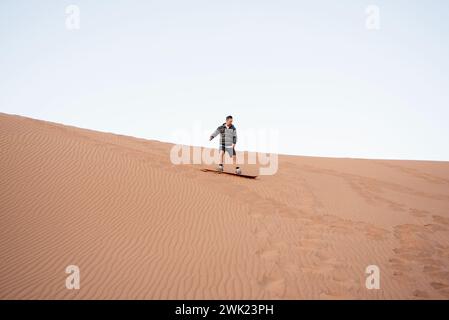 Erg Chigaga, Marocco. 1 febbraio 2024. Adam Kovacs, membro del team KVS, fa sandboarding sulle dune del deserto del Sahara a Erg Chigaga, in Marocco. Il rally amatoriale Budapest-Bamako ha celebrato la quindicesima corsa. È iniziato il 30 gennaio da FES, Marocco, e terminerà il 12 febbraio a Freetown, Sierra Leone. Il percorso originale è stato riorganizzato per ovvi motivi di sicurezza proprio come nella gara Parigi-Dakar, ma allo stesso tempo la distanza è stata estesa. Nel corso degli anni il rally amatoriale Budapest-Bamako è diventato una delle gare più lunghe e impegnative del mondo. (Credito IMA Foto Stock