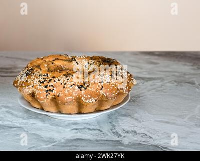 Semi di papavero appena sfornati e muffin all'uva passa cosparso di semi di sesamo su un piatto su un ripiano in pietra Foto Stock