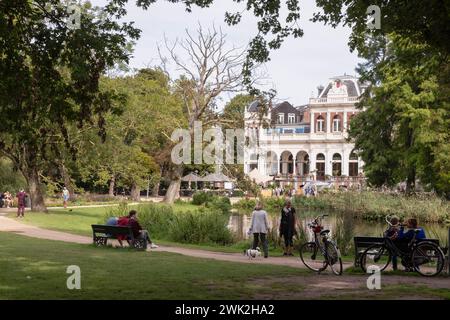 I turisti camminano nel famoso Vondelpark di Amsterdam, con il Vondelpark Pavilion sullo sfondo. Foto Stock