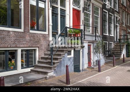 Facciate di case sui canali con gradini di pietra all'ingresso di Amsterdam. Foto Stock