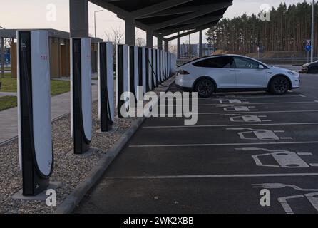 Berlino, Germania - 4 febbraio 2024: Una foto statica della ricarica Tesla Model 3 e Y presso le stazioni di ricarica Gigafactory Supercharger e CA in una soleggiata giornata invernale. Se Foto Stock