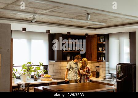 Una scena emozionante si svolge in una cucina domestica mentre una coppia condivide un affettuoso abbraccio, circondato dalla tranquillità della propria casa alla fine di Foto Stock
