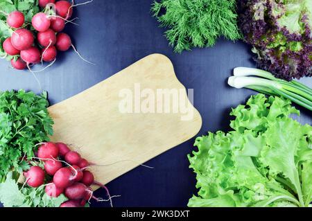 Cetrioli e verdure fresche su un tagliere. Vista dall'alto. Composizione su fondo in legno. Utensili da cucina. Concetto di cibo sano. Foto Stock