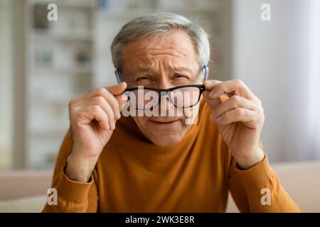 Uomo anziano stanco che rimuove gli occhiali, interni di casa Foto Stock