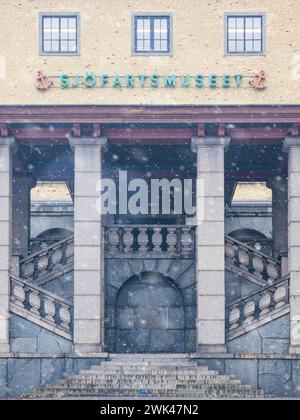 Questa immagine cattura un sereno momento invernale mentre i fiocchi di neve cadono dolcemente di fronte al Sjöfartsmuseet, mettendo in risalto le imponenti colonne dei musei e gran Foto Stock