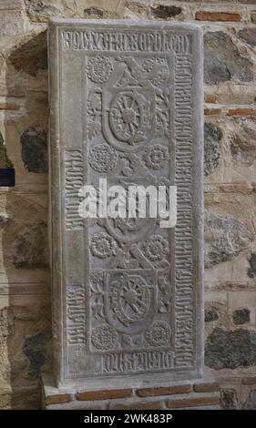 Lapide di Diego de Santa Catalina. Decorazione vegetale. Nella parte centrale, scudi raffiguranti la "ruota di Caterina", strumento con cui St. Caterina (Santa Catalina) fu giustiziata per ordine dell'imperatore Massimiano. Iscrizioni in caratteri gotici maiuscoli al confine. Pietra. xiv secolo. Dalla Chiesa di San Román. Toledo, Spagna. Museo dei consigli e della cultura visigoti. Toledo, Castiglia-la Mancha, Spagna. Foto Stock