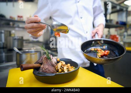 Il dipendente della cucina prepara la carne con verdure e salsa per servire Foto Stock