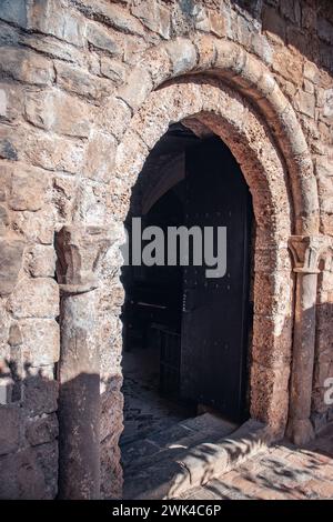 Porta nera che porta alla foto dell'antica chiesa. Fotografie murali in mattoni beige. Ingresso con due persiane. Foto del monastero di Sant Miquel del fai. Ciao Foto Stock