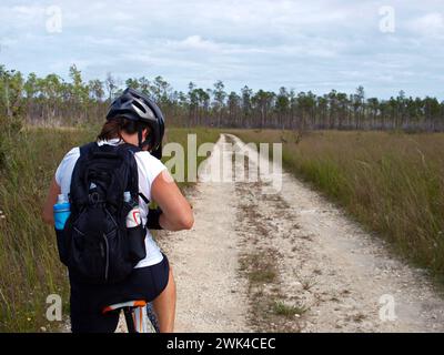 Everglades, Florida, Stati Uniti - 13 settembre 2016: Motociclista donna in Long Pine Key Nature Trail con zaino che porta bottiglie d'acqua Camelback. Foto Stock