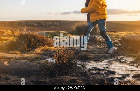 Donna energica che cammina con stivali impermeabili lungo il percorso di trekking con figliuolo congelato nella fredda mattina d'inverno Foto Stock