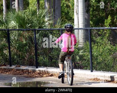 Ragazza in bicicletta in un parco con casco di sicurezza. Foto Stock