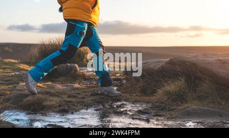 Donna energica che cammina con stivali impermeabili lungo il percorso di trekking con figliuolo congelato nella fredda mattina d'inverno Foto Stock