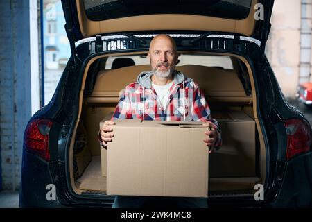 Un uomo siede sul bagagliaio aperto di un'auto Foto Stock