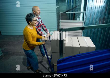 Un uomo e una donna che spingono un carro con scatole di cartone Foto Stock