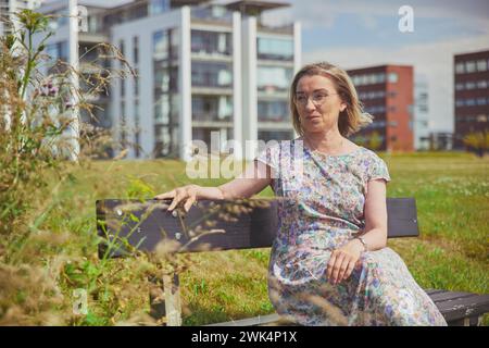 Aalborg, Danimarca, 10 luglio 2022: Bella donna matura su una panchina Foto Stock