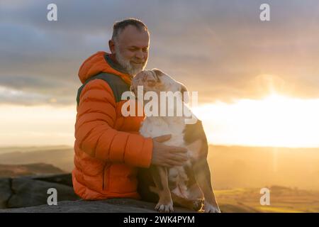 vecchio uomo maturo escursioni in montagna con il suo cane, esercizio fisico e fitness per il benessere, stile di vita sano e sorriso. Faccia di un signore anziano e maturo Foto Stock