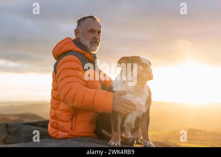 vecchio uomo maturo escursioni in montagna con il suo cane, esercizio fisico e fitness per il benessere, stile di vita sano e sorriso. Faccia di un signore anziano e maturo Foto Stock